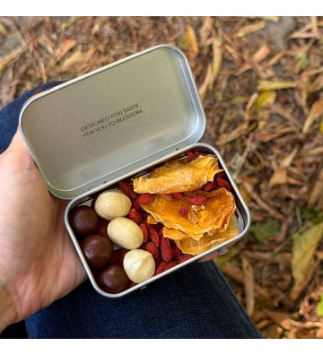 Biossom Snack Tin No. 02 – open tin with fruit, chocolate and nuts next to the product packaging