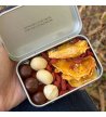 Biossom Snack Tin No. 02 – open tin with fruit, chocolate and nuts next to the product packaging